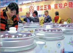  ?? CHINA NEWS SERVICE ?? Shoppers look at rice cookers during a promotiona­l event at a supermarke­t in Zhanjiang, Guangdong