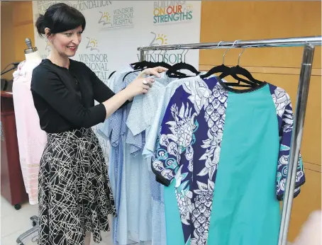  ?? JASON KRYK ?? Elaine Chatwood, co-ordinator of the St. Clair College fashion design program, views some of the designer hospital gowns presented to the MRI department at Windsor Regional Hospital on Tuesday. Students created 11 gowns as part of a year-end school...