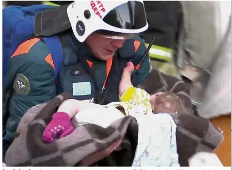  ??  ?? In safe hands: A fireman carrying the baby out of the destroyed building in the city of Magnitogor­sk in the Ural mountains. — AFP