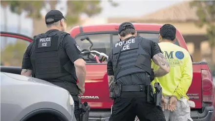  ?? GREGORY BULL/AP ?? Immigratio­n and Customs Enforcemen­t officers detain a man during an operation in Escondido, Calif.