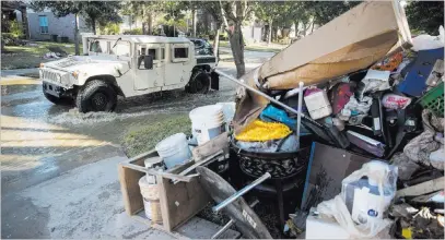  ?? Matt Rourke ?? The Associated Press A military vehicle passes flood-damaged belongings piled on a homeowner’s front lawn Thursday in the aftermath of Hurricane Harvey at the Canyon Gate community in Katy, Texas.