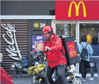  ??  ?? GOLDEN ARCH: Above, a food delivery man leaving a McDonald’s restaurant in Beijing.