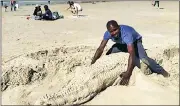  ??  ?? PUZZLING: Michael Myekwa was told to destroy his sand sculptures after asking for money from people who wanted to photograph them.