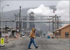  ?? Steph Chambers/ Post- Gazette ?? Mike Trumpe, of Carroll Township, crosses Maple Avenue near U. S. Steel’s Clairton Coke Works in January 2019. The coke- making process produces steam and emissions with a variety of pollutants.