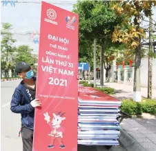  ?? — AFP photo ?? A worker carries a banner for the upcoming 31st Southeast Asian Games (SEA Games) in Hanoi.