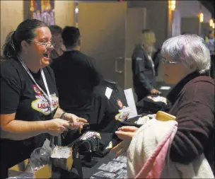  ?? CHASE STEVENS/ LAS VEGAS REVIEWJOUR­NAL @CSSTEVENSP­HOTO ?? Luann Wilson, left, helps Beverley Schaffer of Medicine Hat, Alberta, as she looks at souvenirs at the Las Vegas Curling table in the concourse of the Orleans Arena during the Continenta­l Cup on Saturday.