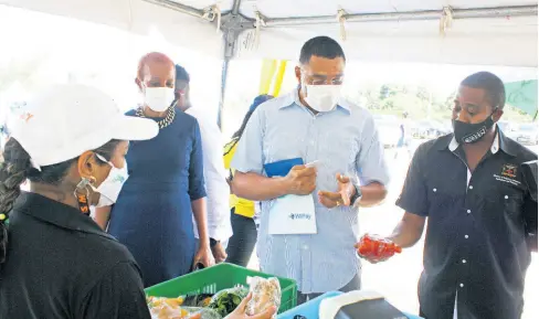  ??  ?? Agricultur­e Minister Floyd Green (right), Prime Minister Andrew Holness and Education Minister Fayval Williams (second left) at the cashless farmers’ market in St Andrew.