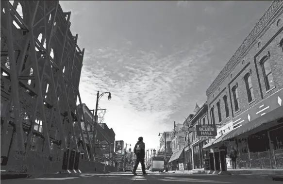  ?? PHOTOS BY JOE RONDONE/THE COMMERCIAL APPEAL ?? March 17, 2020: A lone pedestrian walks down the center of Beale Street during a subdued St. Patrick’s Day celebratio­n.