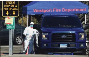  ?? Erik Trautmann / Hearst Connecticu­t Media ?? Workers with Murphy Medical Associates conduct corona virus at a drive-thru testing station on March 24, 2020, at Bedford Middle School in Westport.