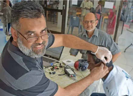  ?? Photo: ?? AHAS Hearing Aid Services consulting audiometri­st Nasif Mohammed (left) fixing a hearing aid on Baram Chand as Labasa Lions Club project director, Hazeem Hussein, looks on at Savilla House in Labasa on January 12, 2018.