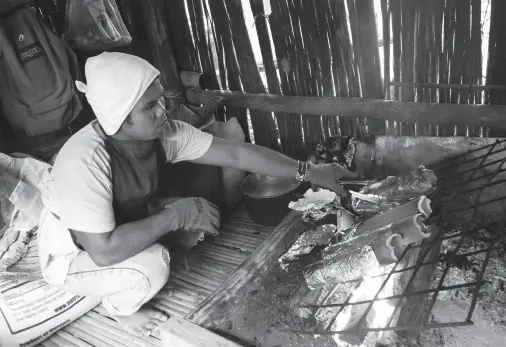  ??  ?? A MEMBER of the Ata tribe shows the way of cooking native chicken using bamboo. The process is called Tinalumbo and it’s sold to visitors at the tribal village inside Magsaysay Park at P150 each. BING GONZALES