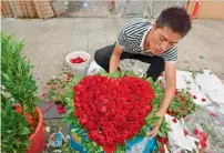  ?? AFP ?? A florist preparing a heart-shaped bouquet of roses ahead of China’s Valentine’s Day, at a flower market in Beijing. —