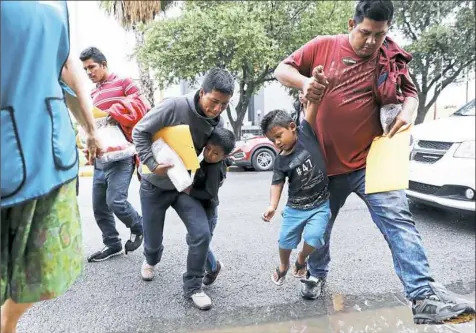  ?? Eric Gay/Associated Press ?? Young immigrants are lifted over a puddle as they arrive with their parents at a Catholic Charities center after they were processed and released by U.S. Customs and Border Protection on Tuesday in McAllen, Texas.