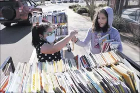  ?? K.M. Cannon Las Vegas Review-Journal @KMCannonPh­oto ?? First grader Tatiana Melgoza, 6, left, and second grader Thelma Castro-Rodriguez, 8, choose books at a school supply event Wednesday at McCaw STEAM Academy in Henderson.