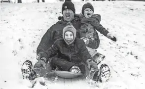  ?? AUGUST FRANK/AP ?? Dion Smith rides a sled with his son Isaac Smith, front, 5, and his daughter Mya Smith, 4, at Hereth Park in Lewiston, Idaho, on Monday.