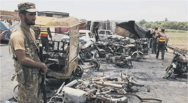  ??  ?? 0 Pakistani soldiers stand guard beside burnt out vehicles at the scene where the oil tanker caught fire following a road accident
PICTURE: SS MIRZA/AFP/GETTY IMAGES