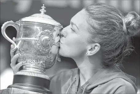  ?? Michel Euler Associated Press ?? SIMONA HALEP of Romania kisses the trophy as she celebrates winning the 2018 French Open title at Roland Garros in Paris.