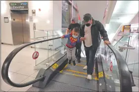  ??  ?? Yancarlos Amaya leaps off an escalator while holding the hand of family friend Dimas Barahona at the airport.