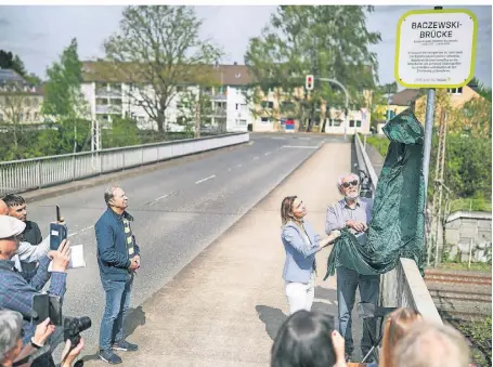  ?? FOTO: STEPHAN KÖHLEN ?? Die Bahnbrücke wird zur Baczewski-Brücke (von links): Bürgermeis­terin Bettina Warnecke und Zeitzeuge Udo KochMehrin enthüllen das Schild.
