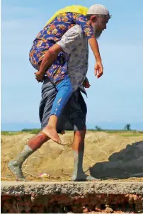  ?? Reuters ?? A Rohingya refugee carries a woman after crossing the Bangladesh-Myanmar border by boat through the Bay of Bengal in Shah Porir Dwip, Bangladesh, on Friday. —