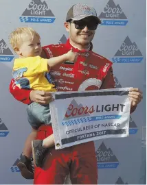  ?? AP PHOTO ?? HE’S GOT HIS HANDS FULL: Kyle Larson holds his son Owen and the pole position flag after winning the top spot in Friday qualifying for today’s NASCAR Cup Series race at Auto Club Speedway in Fontana, Calif.