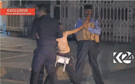  ?? KURDISTAN 24 TV VIA AP ?? A child is restrained by security officers, who hold out his arms as a belt of explosives is removed Sunday in Kirkuk, Iraq.