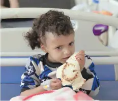  ??  ?? A child suffering from a diphtheria infection, nibbles a piece of bread on a hospital bed in the capital Sanaa. — AFP