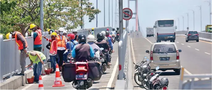  ?? AHMAD KHUSAINI/JAWA POS ?? DEADLINE MEI TAHUN DEPAN: Pekerja mengecat pagar Jembatan Suramadu kemarin. Pengerjaan dikebut agar bisa selesai tepat waktu.