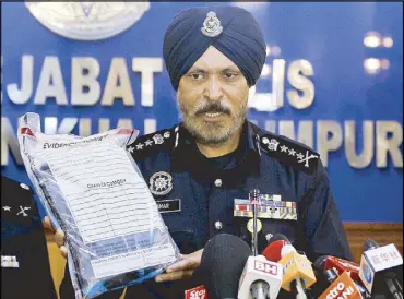  ?? AP ?? Kuala Lumpur police chief Amar Singh shows the belongings of a detained suspect to reporters during a press conference in Malaysia on Saturday.