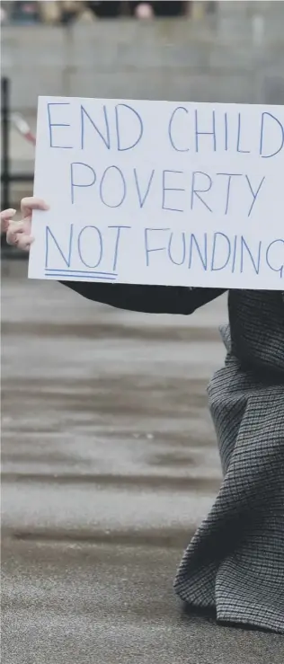  ??  ?? 0 Laura Martin, with her two- year- old daughter Remy, take part in a protest against child poverty and proposed cuts to charity funding in Glasgow