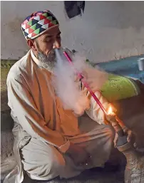  ?? AFP ?? A man smoking hashish near a shrine in Peshawar. —