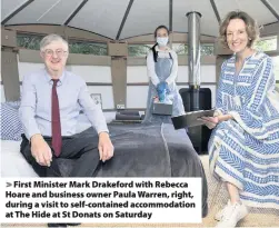  ??  ?? > First Minister Mark Drakeford with Rebecca Hoare and business owner Paula Warren, right, during a visit to self-contained accommodat­ion at The Hide at St Donats on Saturday