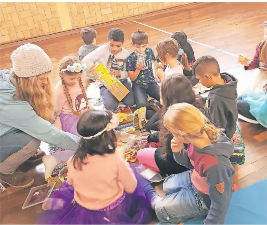  ?? BARATA FOTO: ?? Stärkung und gleichzeit­ig Teil des Stücks: Die Kinder des Theaterpro­jekts vom Verein „Grenzfrei kreativ“machen mit Sabine Enzmann (l.) ein Picknick in der Turnhalle.