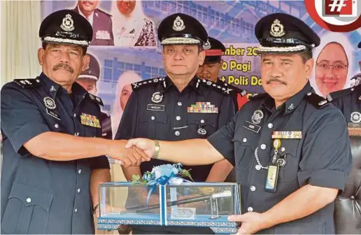  ?? PIC BY FAIZ ANUAR ?? Kuala Selangor police chief Superinten­dent Ruslan Abdullah ( left) handing over duties to his successor, Deputy Superinten­dent Mohd Asri Abdul Wahab, at the district police headquarte­rs in Kuala Selangor yesterday. With them is state police chief Datuk...