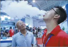  ?? XIAO CHEN / FOR CHINA DAILY ?? A visitor watches an assistant demonstrat­e “cloud chasing” at an e-cigarette exhibition in Beijing in July.
