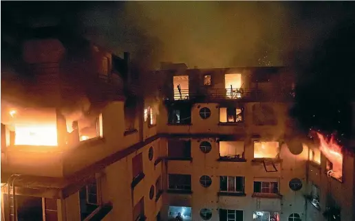  ?? AP ?? A fire rages through the top floors of an apartment building in Paris, France. The fire that authoritie­s suspect was an arson attack sent residents fleeing to the roof or climbing out their windows to escape.