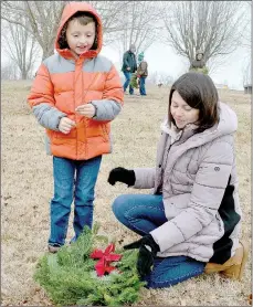  ?? Keith Bryant/The Weekly Vista ?? Harrison Goodner, 7, lays a wreath on a veteran’s grave marker with some help from his mother, Lindsey Goodner.