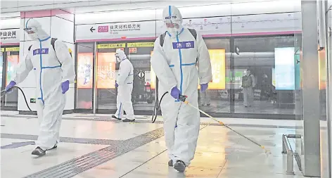  ?? — AFP file photo ?? Staff members spray disinfecta­nt at a subway station in Wuhan, in China’s central Hubei province, as the subway prepares to reopen to the public after closing due to the Covid-19 coronaviru­s outbreak.