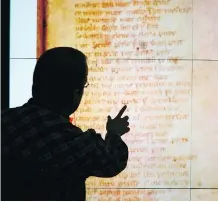  ?? SALMAAN FAROOQUI ?? John Brosz, visualizat­ion research co-ordinator at the University of Calgary, examines an enlarged manuscript on the school’s 35-million-pixel screen. It reveals hidden history and meaning.