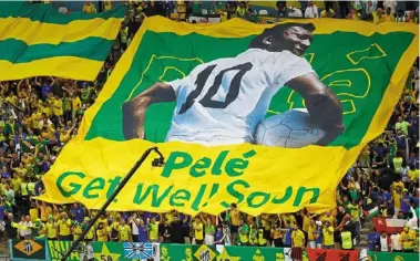  ?? — Reuters ?? Clear message: brazil fans display a banner with an image of Pele before the match against cameroon. The brazil legend was hospitalis­ed this week with respirator­y infection but remains in stable condition.