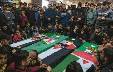  ?? FATIMA SHBAIR/AP ?? Mourners gather around the coffins of four out of eight Palestinia­n migrants who died off the Tunisian coast, at their funeral Dec. 18 at a mosque in Rafah in the Gaza Strip. A growing number of Gazans, seeking better lives, are dying at sea.