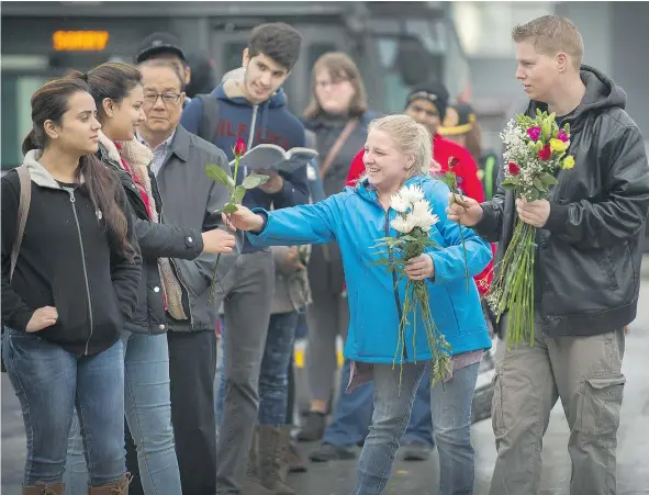  ?? ARLEN REDEKOP/PNG ?? Rhiannon Paskall and her fiancé Jonah hand out flowers to strangers at the Newton bus exchange in Surrey last week. Rhiannon, whose mother was killed outside Newton Arena in 2013, is part of a grassroots effort to make the area more welcoming.
