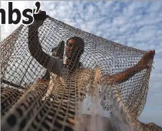  ??  ?? A man repairs a fishing net on his boat on the Tonle Basac River in Phnom Penh, Cambodia, on Jan 20, 2017.