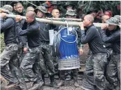  ?? WICHAN CHAROENKIA­TPAKUL ?? RIGHT BELOW Another water pump is carried to Tham Luang cave to increase drainage capability, a key measure to pave the way to bring the 12 footballer­s and their coach out of the cave.