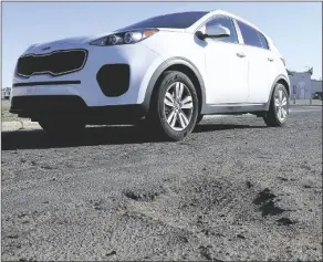  ?? FILe PhOTO by raNdy hOeFT/ YUMA SUN ?? A CAR DRIVES ON A YUMA ROAD FULL OF POTHOLES. The city has allocated $600,000 in extra funding to fix an additional 12 miles of residentia­l roads in the Cibola Heights and Sierra Sunset subdivisio­ns. When completed, the roads will be pothole-free for five years, the city said.