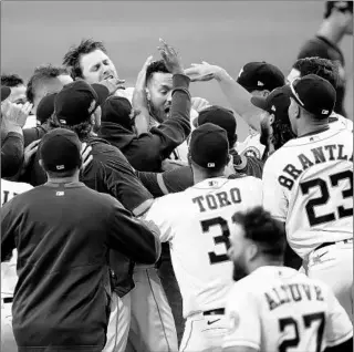  ?? SEAN M. HAFFEY/GETTY ?? Astros players mob Carlos Correa after his walk-off home run in Game 5 of the ALCS on Thursday.