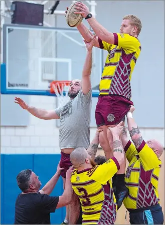  ??  ?? Above, Jeff Rochester, left, and Alex Frederick, right, reach for a ball during a “line-out drill” Feb. 5 during a practice of the New London County Rugby Football Club at Lyme-Old Lyme High School.