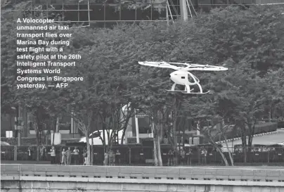  ??  ?? A Volocopter unmanned air taxi transport flies over Marina Bay during test flight with a safety pilot at the 26th Intelligen­t Transport Systems World Congress in Singapore yesterday. — AFP