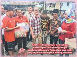  ??  ?? IKHLAS: Fadillah (tengah) memeluk dan menenangka­n salah seorang mangsa kebakaran di Kampung Tupong Jaya pada majlis penyampaia­n sumbangan di Kuching, semalam.