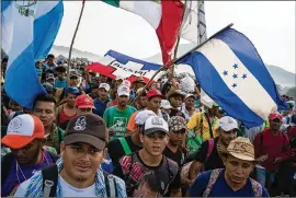  ?? TODD HEISLER/THE NEW YORK TIMES ?? Migrants carry flags of El Salvador, Mexico and Honduras as they make their way toward the U.S. as part of a caravan. Anyone making it to the border has a right to request asylum.